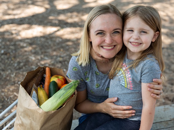 Woman and child next to a bag of groceries